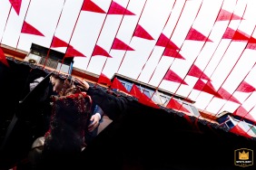 At the entrance of the corridor in Taiyuan, Shanxi, the groom lifts the bride as she gets into the wedding car, with repeating red pendant flags hanging overhead.